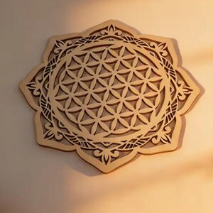 Könnte beinhalten: Wandkunst aus Holz mit einem detaillierten Flower-of-Life-Design. Das Kunstwerk ist aus hellem Holz geschnitten und hat eine symmetrische, blütenartige Form. Das geometrische Muster ist geschichtet.