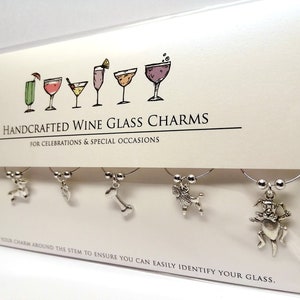 K&ouml;nnte beinhalten: Satz mit sechs silbernen Weinglasanh&auml;ngern mit verschiedenen Tiermotiven. Die Anh&auml;nger sind auf einer wei&szlig;en Karte mit dem Text "HANDCRAFTED WINE GLASS CHARMS FOR CELEBRATIONS & SPECIAL OCCASIONS HOOK YOUR CHARM AROUND THE STEM TO ENSURE YOU CAN EASILY IDENTIFY YOUR GLASS." abgebildet.