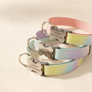 Puede incluir: Tres collares para mascotas con un patrón tie-dye en tonos pastel de rosa, amarillo y azul. Cada collar incluye una hebilla de metal plateado con forma de hueso, grabada con el nombre LUCKY y el número de teléfono ficticio 000-0000-0000.