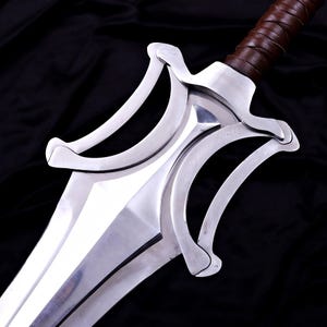 May include: A close-up of a silver sword with a polished blade and ornate guard. The hilt is wrapped in brown leather. The sword is set against a black background.