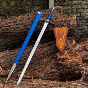May include: A silver-toned metal sword with a blue wrapped handle and a matching blue scabbard featuring silver metal accents. Beside the sword is a shield-shaped wall plaque in a reddish-brown color with a yellow decorative line pattern.