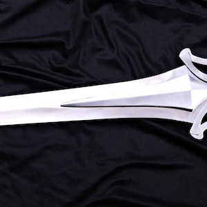 May include: A polished, silver-colored sword with a double-edged blade. The hilt features a decorative, curved design. The sword is displayed against a black fabric background.