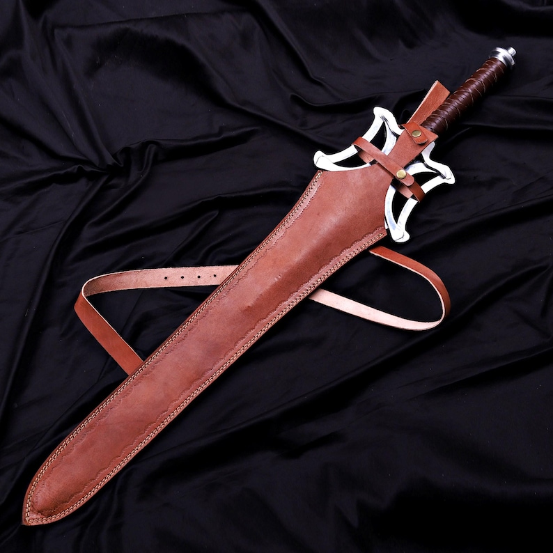 May include: A medieval-style sword with a brown leather sheath and handle. The sword features a silver-colored blade and guard, and a leather strap for carrying. The sheath is stitched along the edges.