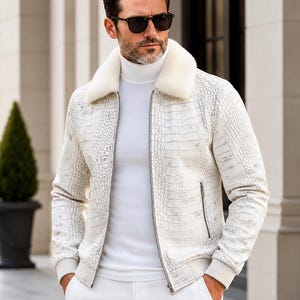 May include: A white jacket with a textured crocodile skin pattern, a plush white faux fur collar, and a silver front zipper. The jacket features ribbed cuffs and hem, paired with a white turtleneck sweater and white trousers.