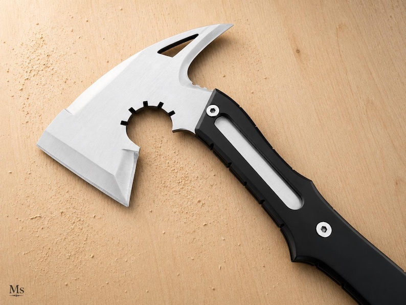 May include: A tactical hatchet featuring a silver-colored metal head with a sharp blade, a curved cutout, and a pointed spike. The handle is black with a central silver inlay and is secured by two visible silver screws near the axe head.