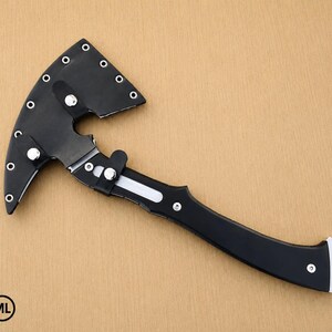 May include: A black hatchet with a curved blade encased in a matching black sheath. The sheath features silver-colored metal rivets along the edge and a snap closure. The handle is black with silver accents and a hole at the end for hanging.