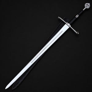 May include: A long steel sword with a double-edged blade and a central fuller. The hilt features a black leather-wrapped grip, a silver crossguard with twisted metal detailing, and a circular pommel with a wolf head emblem at the end.