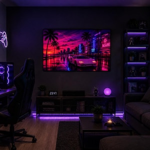 Può includere: Una sala giochi illuminata al neon con un grande schermo che mostra un paesaggio urbano di Miami al tramonto. La stanza presenta un PC da gioco, una sedia da gioco nera e un divano. Le luci a LED viola illuminano la stanza.