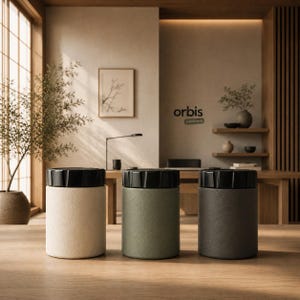 May include: Three cylindrical canisters with textured matte finishes in cream, sage green, and charcoal gray. Each container features a black, ridged, screw-top lid. The canisters are arranged in a row on a wooden surface, displaying a uniform design.