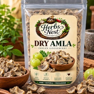 Op de afbeelding: Een doorzichtige plastic zak met gedroogde amla, of Indiase kruisbes, van het merk Herbs Nest. Het etiket bevat de tekst Herbs Nest, Dry Amla, Indian Gooseberry en Pure, Natural, Wholesome. Het bevat iconen voor 100% natuurlijk, rijk aan vitamine C, ondersteunt de immuniteit en premium kwaliteit, met afbeeldingen van verse en gedroogde kruisbessen.