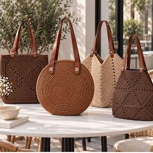 Könnte beinhalten: Vier gehäkelte Tragetaschen mit braunen Lederriemen. Eine dunkelbraune quadratische Tasche, eine runde mittelbraune Tasche, eine beige V-förmige Tasche und eine dunkelbraune Tasche mit Dreiecksmuster. Alle Taschen haben stabile Tragegriffe.