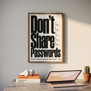 May include: A framed poster with the words "Don't Share Passwords" in bold black letters. The poster includes a list of password security tips. A laptop, headphones, books, and a small cactus sit on a desk.