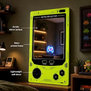 May include: A rectangular wall mirror with a bright lime green frame designed to resemble a vintage handheld gaming console. The frame features black printed details including a directional pad, A and B buttons, and the text Retro Reflector.