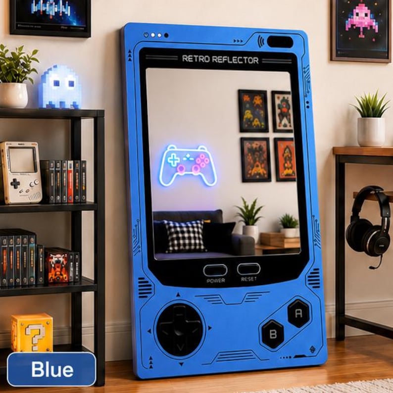 May include: A large blue floor mirror shaped like a vintage handheld gaming console. The frame features black directional buttons, A and B buttons, and labels for power and reset. The screen area displays a glowing neon white game controller.