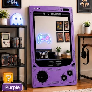 May include: A large purple floor mirror shaped like a handheld video game console. The frame features printed circuit board patterns, a directional pad, A and B buttons, and power and reset labels. The top displays the text RETRO REFLECTOR.