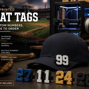 Peut inclure: Casquette de baseball bleu marine avec un numéro 99 blanc et argenté. En dessous, plusieurs étiquettes de chapeau imprimées en 3D avec différents numéros de couleurs variées, dont le bleu, le blanc, l'or et le noir. Le texte "3D PRINTED HAT TAGS" est en haut.