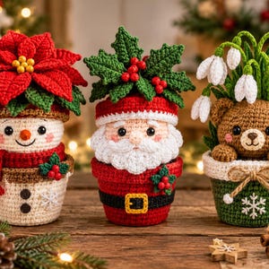 May include: Three crocheted figures in pots: a snowman with a red poinsettia, a Santa Claus with holly leaves and berries, and a brown bear with white snowdrop flowers. Each figure is crafted with yarn, featuring detailed facial expressions.