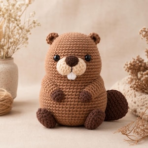 May include: A crochet beaver stuffed animal made with medium brown yarn for the body, darker brown yarn for the paws and tail, and light beige yarn for the muzzle. It features two black plastic eyes, a dark brown nose, and one white tooth.