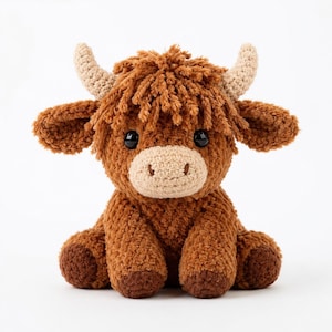 May include: A handmade, plush Highland cow toy. The soft, brown cow has a shaggy coat, tan horns, and a light tan muzzle. The toy has black safety eyes and is sitting with its legs tucked in. A cute, cuddly stuffed animal.