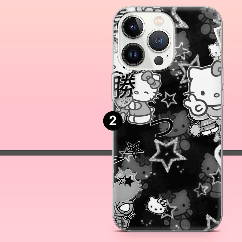 Puede incluir: Funda de tel&eacute;fono en blanco y negro con un patr&oacute;n repetido de personajes de Hello Kitty, estrellas y texto japon&eacute;s. La funda tiene un borde transparente y un fondo negro. El n&uacute;mero "2" es visible en la funda.