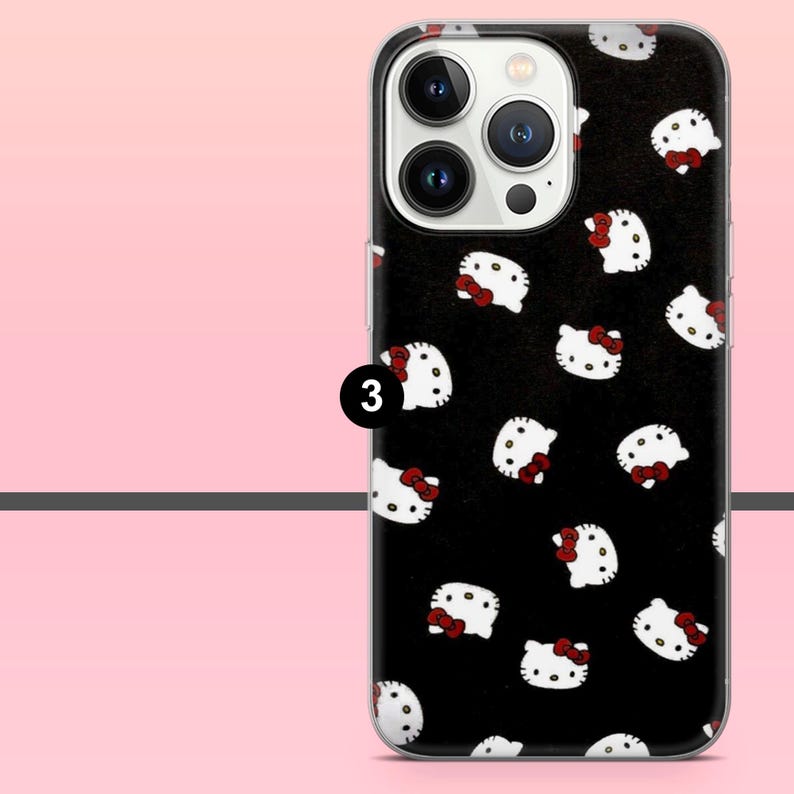 Puede incluir: Funda de tel&eacute;fono negra con un patr&oacute;n de caras de gato blanco de dibujos animados con lazos rojos. La funda tiene un borde transparente y un recorte para la c&aacute;mara. El n&uacute;mero "3" es visible en el lateral.