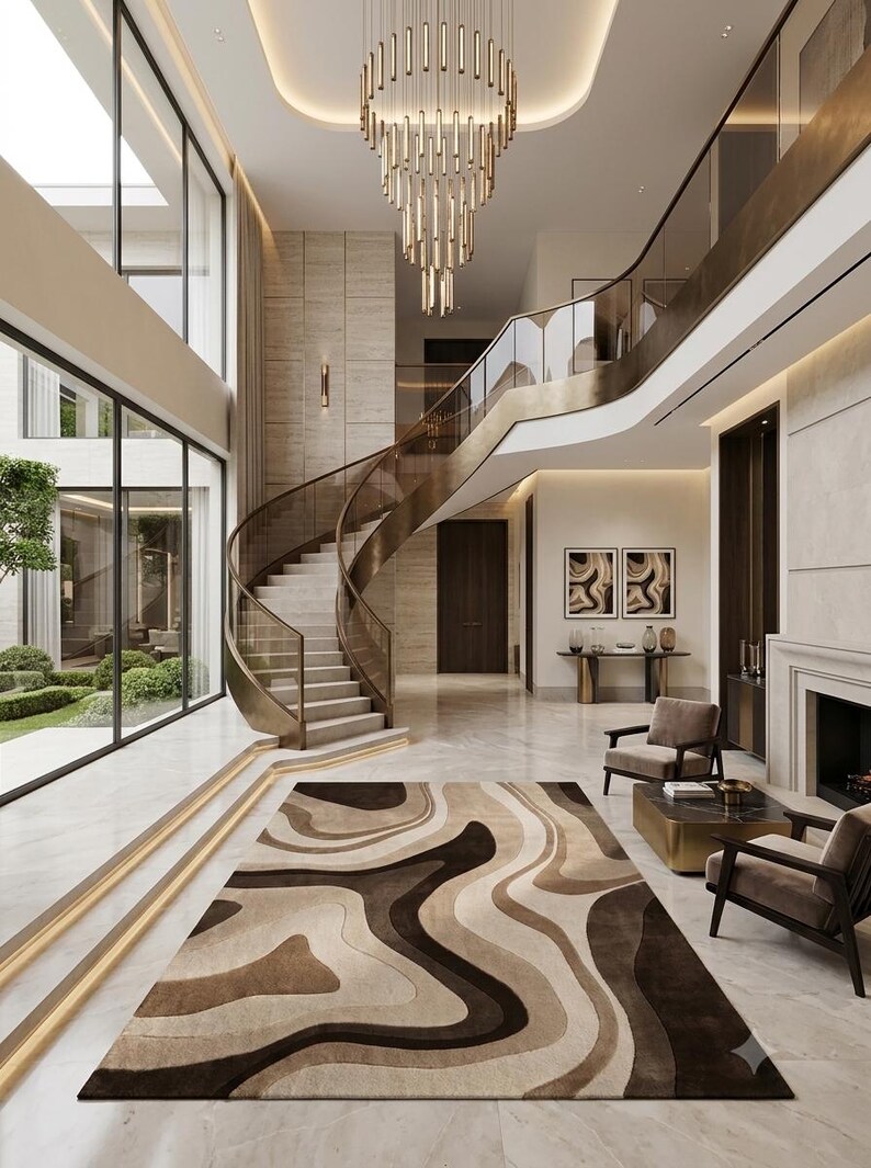 May include: A rectangular area rug featuring a flowing, abstract pattern of layered wavy lines in shades of dark brown, tan, and cream. The rug is positioned on a polished light-colored stone floor in a spacious, multi-level interior entryway.