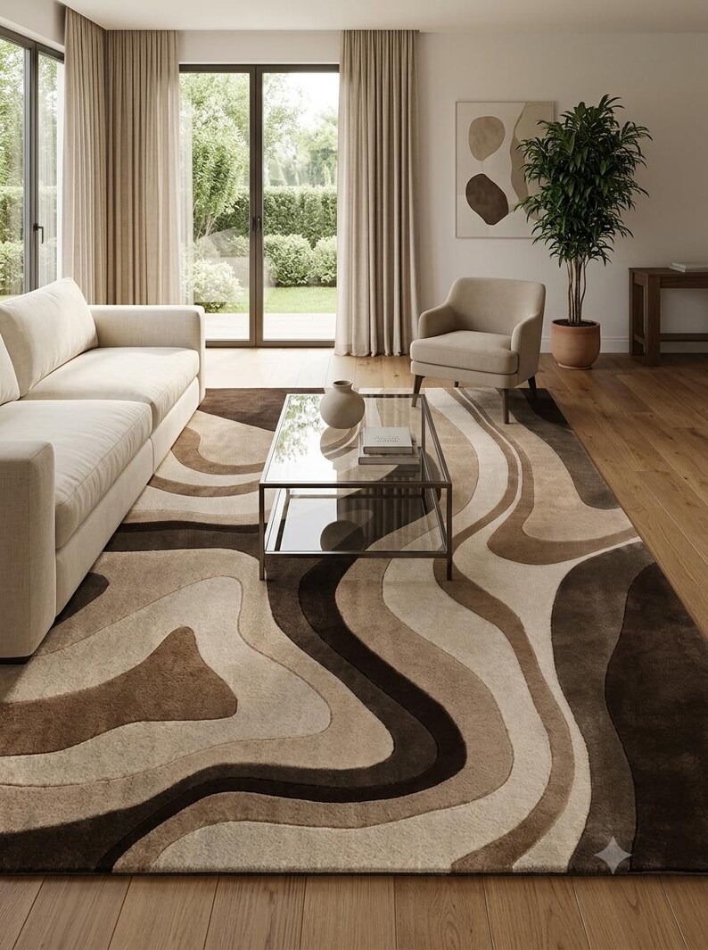 May include: A large rectangular area rug featuring a flowing, organic pattern of wavy, layered bands in shades of cream, beige, tan, and dark chocolate brown. The rug has a soft, textured pile and covers a significant portion of the wooden floor.