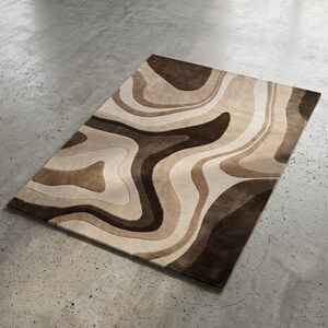 May include: A rectangular area rug featuring a layered, wavy pattern in various shades of brown, tan, and cream. The design consists of fluid, organic shapes that create a sense of depth and movement across the surface of the floor covering.