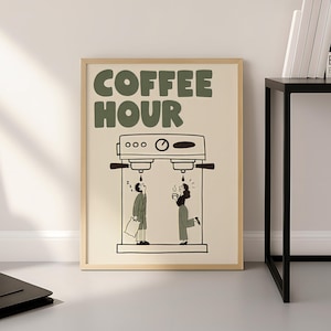 Könnte beinhalten: Ein gerahmter Kunstdruck mit dem Text COFFEE HOUR in großen grünen Buchstaben. Die Illustration zeigt eine Espressomaschine im Strichzeichnungsstil mit zwei Personen darunter, eine im Schlafanzug mit Kissen und eine mit dampfender Tasse.