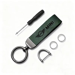 May include: A green leather keychain with the word "MINI" and a logo, a black screwdriver, two small silver rings, and a silver D-ring. The keychain has a large black ring for keys.