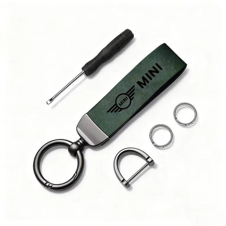 May include: A green leather keychain with the word "MINI" and a logo, a black screwdriver, two small silver rings, and a silver D-ring. The keychain has a large black ring for keys.