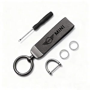 May include: A black leather keychain with the word "MINI" and the MINI logo. Includes a small screwdriver, two key rings, and a D-ring. The keychain is dark gray with a silver-colored metal accent.