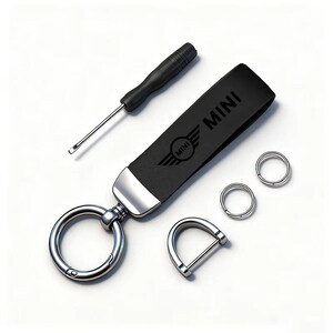 May include: A black leather key fob with the word "MINI" and the MINI logo, a screwdriver, two small key rings, and a D-shaped clasp. The key fob has a silver-colored metal accent and a large key ring.