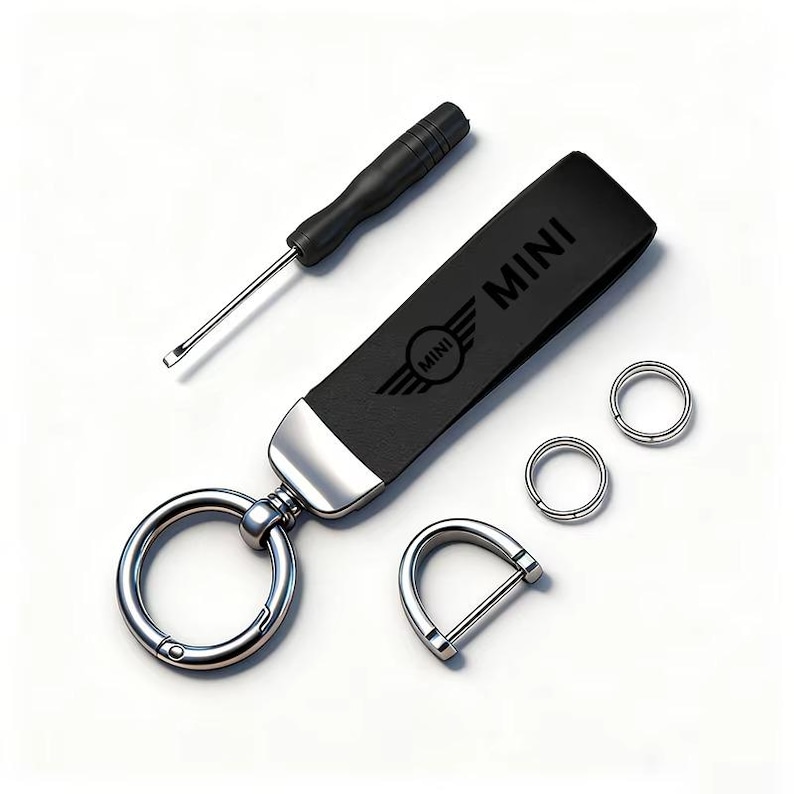 May include: A black leather key fob with the word "MINI" and the MINI logo, a screwdriver, two small key rings, and a D-shaped clasp. The key fob has a silver-colored metal accent and a large key ring.