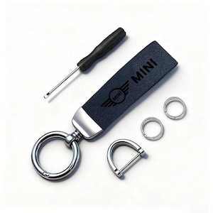 May include: A navy blue leather keychain with the word "MINI" and logo, a screwdriver, and metal rings. The keychain has a silver metal clasp and a D-shaped metal piece. The items are on a white background.