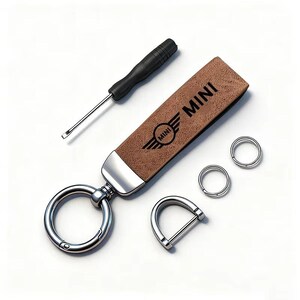 May include: A brown leather key fob with the word "MINI" and logo, a silver key ring, two small silver rings, a silver D-ring, and a black screwdriver. The key fob is rectangular with a silver metal end.