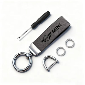 May include: A gray leather keychain with the word "MINI" and the MINI logo, a screwdriver, and several metal rings. The keychain has a silver metal clasp and a D-ring. The items are on a white background.