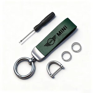 May include: A green leather keychain with the word "MINI" and a logo, a screwdriver, and several metal rings. The keychain has a large silver ring and a silver D-shaped clasp. The items are on a white background.