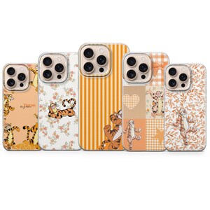 Pode incluir: Cinco capas de telemóvel com a personagem Tigrão de Winnie the Pooh. Os designs incluem riscas laranja, padrões florais e patchwork com corações e estrelas. As capas são em tons de laranja, branco e bege.
