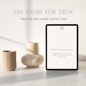 May include: A tablet displaying the text EIN RAUM FÜR DICH, FÜHLZEIT Begegnungen, and Interaktive Begegnungen mit Körper, Sinnen, Gefühlen & Bedürfnissen, positioned next to a ribbed beige cup and a smooth beige vase with a rounded base.