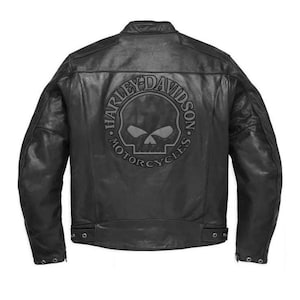 May include: A black leather motorcycle jacket featuring a large circular embossed graphic on the back. The design includes a central skull icon surrounded by the text Harley-Davidson Motorcycles. The jacket has long sleeves and snap closures.