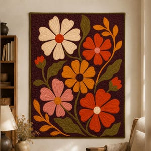 May include: A rectangular wall quilt featuring a dark brown background with a large floral pattern. The design includes five prominent flowers in shades of cream, orange, pink, and red, accompanied by green leaves and stems with visible stitching.