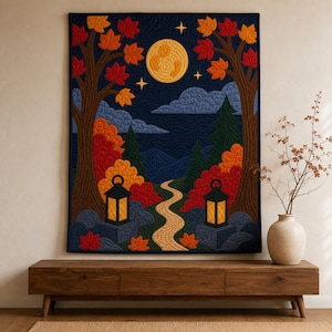 May include: A rectangular wall quilt featuring a nighttime forest scene with two large trees, a winding path, and two lanterns. The design includes a full moon, stars, and autumn-coloured leaves in shades of red, orange, and yellow against a dark blue sky.