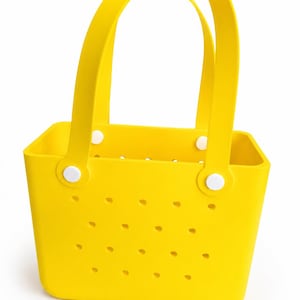 May include: Bright yellow tote bag with two curved handles and a rectangular body. The bag features small, evenly spaced holes and is secured with white circular fasteners. The bag is made of a flexible material.