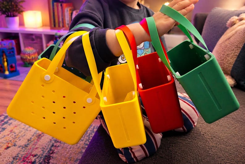 May include: A collection of colorful tote bags in yellow, yellow, red, and green. The bags have handles and are held together. The yellow bag has multiple holes. The bags are made of a durable material.
