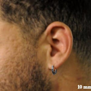 May include: A silver hoop earring with a 10 mm diameter. The earring is worn in the left ear of a person with short brown hair.