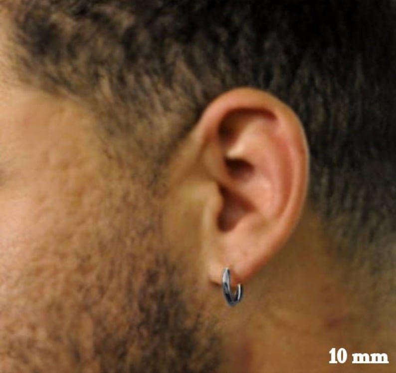 May include: A silver hoop earring with a 10 mm diameter. The earring is worn in the left ear of a person with short brown hair.