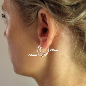May include: Two silver hoop earrings with gold beads. The larger hoop is 15mm in diameter and the smaller hoop is 12mm in diameter.