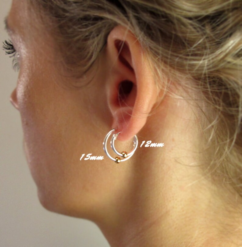 May include: Two silver hoop earrings with gold beads. The larger hoop is 15mm in diameter and the smaller hoop is 12mm in diameter.