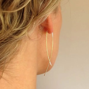 May include: Gold-toned, long, thin, delicate, open hoop earrings with a criss-cross design.